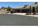 Spacious home featuring a three-car garage, complemented by desert landscaping and a red car at 9753 Arrowcrest Ave, Las Vegas, NV 89147
