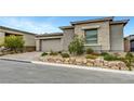 Single-story home with a stone facade, two-car garage, and beautifully landscaped front yard at 977 Edinburgh Fields Ct, Las Vegas, NV 89138