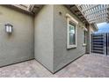 Covered patio with stone flooring and stucco walls, featuring a modern light fixture at 977 Edinburgh Fields Ct, Las Vegas, NV 89138