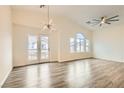 Open concept living space with modern light fixture, doors to balcony, and large windows providing ample light at 10147 Aspen Rose St # 101, Las Vegas, NV 89183