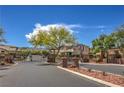 Community gated entrance with brick pillars, desert landscaping and mature trees on a sunny day at 10319 Larkmead Ave, Las Vegas, NV 89149