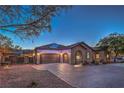 Charming home at twilight featuring a paved driveway, a three car garage, desert landscaping and solar panels at 10319 Larkmead Ave, Las Vegas, NV 89149