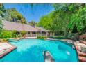 Backyard swimming pool area surrounded by lush greenery with diving board and hot tub at 108 Quail Run Rd, Henderson, NV 89014
