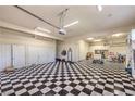 Spacious garage with black and white checkered flooring, white storage cabinets, and bright overhead lighting at 2086 Troon Dr, Henderson, NV 89074