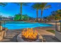 Backyard pool with stone accents, fire pit, palm trees, and lush landscaping at 2086 Troon Dr, Henderson, NV 89074