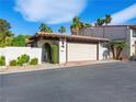 Attached two-car garage with white door, brick trim, and red tile roof, nestled among palm trees and white brick walls at 2104 Plaza De La Candela, Las Vegas, NV 89102