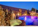 Backyard oasis featuring a rock waterfall, heated spa, and a built-in outdoor kitchen at 2124 Pont National Dr, Henderson, NV 89044