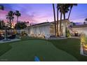 Expansive backyard featuring an artificial putting green, a seating area, and mature palm trees in a desert setting at 219 Windsong Dr, Henderson, NV 89074