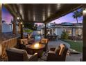 Relaxing covered patio with a fire pit and comfortable seating, overlooking the pool and backyard at 219 Windsong Dr, Henderson, NV 89074