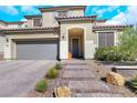 Two-story home with desert landscaping, tile roof, and a two car garage with brick paver driveway at 3512 Portiani Dr, Las Vegas, NV 89141
