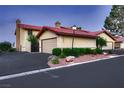 Townhouse with a two-car garage and red tile roof with manicured landscaping at 3942 Delos Dr, Las Vegas, NV 89103