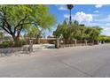 Front exterior featuring mature trees and an ornate gated entrance with a circular driveway at 5854 Sheila Ave, Las Vegas, NV 89108