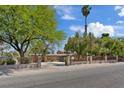 View of home showcasing wrought iron gate, mature trees, and circular driveway at 5854 Sheila Ave, Las Vegas, NV 89108