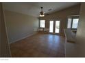 Spacious living room with neutral walls, tile flooring, a ceiling fan, and access to a patio at 7518 Luna Del Rey St, Las Vegas, NV 89123