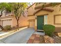 Stylish two-story townhome showcases low-maintenance landscaping, an attached garage, and an attractive green front door at 7923 Homer Ct, Las Vegas, NV 89139
