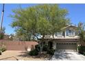 Inviting two-story home with a well-manicured front yard, mature tree, and a two-car garage at 8682 Gateway Glen Dr, Las Vegas, NV 89178