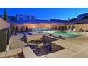 Backyard pool with elegant landscaping, water feature, and cozy sunken seating area and fire pit at 881 Barrhead Ave, Henderson, NV 89012