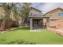A well-maintained backyard featuring a covered patio and artificial grass for a low maintenance, green outdoor space at 9545 Parker Springs Ct, Las Vegas, NV 89166