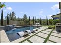 A modern backyard features a sparkling pool with lounge chairs and a waterfall, and lush landscaping for a tranquil retreat at 10297 Sierra Skye Ave, Las Vegas, NV 89166
