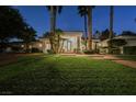 Well-maintained single-story home with a sprawling front lawn and mature palm trees, enhanced by exterior lighting at 2231 S Tioga Way, Las Vegas, NV 89117
