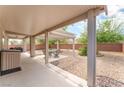 Inviting covered patio with fan, plus a seating area and desert landscaping perfect for outdoor living at 2413 Mourning Warbler Ave, North Las Vegas, NV 89084