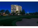 Nighttime exterior shot of a high-rise building overlooking a golf course with the Las Vegas skyline in the background at 3111 Bel Air Dr # 7F, Las Vegas, NV 89109