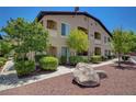 Tan two-story condo building featuring well-maintained landscaping and a red tile roof at 3320 Cactus Shadow St # 201, Las Vegas, NV 89129