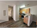 Open-concept kitchen with wood cabinets, white appliances, breakfast bar, and wood-look flooring in a well-lit space at 4730 E Craig Rd # 1106, Las Vegas, NV 89115