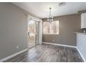 Dining area features modern light fixture, wood-look flooring, and sliding glass door to balcony at 6873 Tamarus St # 201, Las Vegas, NV 89119
