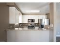 Open kitchen features white cabinets, stainless appliances, and a breakfast bar at 6873 Tamarus St # 201, Las Vegas, NV 89119