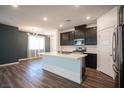 Open-concept kitchen with dark cabinets, stainless steel appliances, a large island, and wood-look floors at 871 Aurelie Ridge St, Henderson, NV 89011