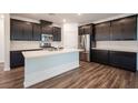 Modern kitchen with dark cabinets, stainless steel appliances, and a large island with quartz countertops at 871 Aurelie Ridge St, Henderson, NV 89011