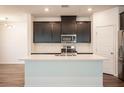 Bright kitchen features dark cabinets, stainless steel appliances, a large island, and sleek, modern lighting at 871 Aurelie Ridge St, Henderson, NV 89011