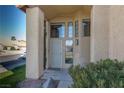 Welcoming front entrance with decorative door, ample windows, desert landscaping, and a well-maintained lawn at 1942 Old Mill Ln, Henderson, NV 89014