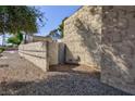 Side yard features a textured wall, gravel landscape, and a small blue gate at 45 N Lamb Blvd, Las Vegas, NV 89110