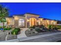 Charming single-story home with a stucco facade, stone accents, and landscaped front yard at dusk at 6230 Calm Brook Ct, Las Vegas, NV 89149