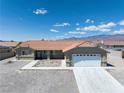 Wide shot of a single-story home with desert landscaping, a red tile roof, and a two-car garage at 654 Mazelle Ln, Pahrump, NV 89060
