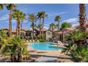 Community pool surrounded by lush landscaping and palm trees for a relaxing resort-style living experience at 8000 Badura Ave # 1007, Las Vegas, NV 89113