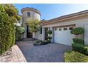 A beautiful single-Gathering home with a rounded tower entry, brick driveway, and well-manicured landscaping at 9301 Queen Charlotte Dr, Las Vegas, NV 89145
