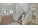 Bright hallway with stairway, neutral carpet, and tile flooring leading to a powder room with a pedestal sink at 10198 Eden Mountain St, Las Vegas, NV 89141