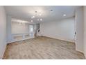 Bright living room with wood-look tile flooring, contemporary lighting, and neutral paint at 10598 Aphrodite St, Las Vegas, NV 89183