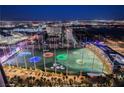 Nighttime view of a brightly lit Topgolf facility as seen from a high-rise balcony, overlooking the city at 135 E Harmon Ave # 2420, Las Vegas, NV 89109