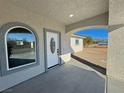 Stucco home featuring white front door, an arched window, and a covered front porch at 1580 S Tiptop Trl, Pahrump, NV 89048