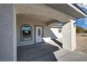 View of covered front porch with arched window, stucco walls, and white front door at 1580 S Tiptop Trl, Pahrump, NV 89048