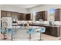 Modern kitchen featuring dark wood cabinetry, granite countertops, stainless steel appliances and island seating at 245 Hull St, Henderson, NV 89015