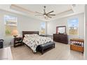 Comfortable main bedroom with a ceiling fan, tray ceiling, and light wood-look flooring at 245 Hull St, Henderson, NV 89015