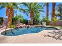 Backyard pool features mature palm trees, a stone waterfall, and a basketball hoop for entertainment at 2500 Wimbledon Dr, Las Vegas, NV 89107