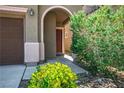 Inviting arched entryway, featuring a stained wood front door and lush shrubbery at 4786 Castel Martini Ct, Las Vegas, NV 89147