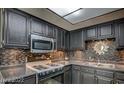 Well-lit kitchen featuring sleek black cabinetry, stainless steel microwave, and a modern backsplash at 6463 Big Pine Way, Las Vegas, NV 89108