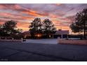 A beautiful sunset view of the residence with a spacious driveway, mature trees and block wall at 8365 S Hauck St, Las Vegas, NV 89139